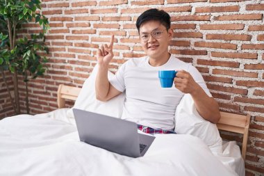 Genç Asyalı bir adam yatakta oturmuş kahve içerken bir fikre ya da soru işaretine şaşırdı. 