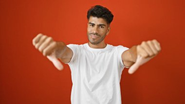 Yakışıklı İspanyol adam kırmızı duvara başparmak işareti yapıyor..