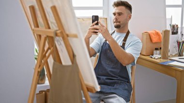 Yakışıklı İspanyol bir adam resim stüdyosunda telefonuyla selfie çekiyor..