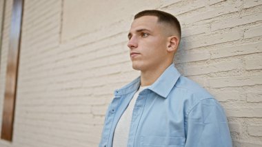 Sıradan giyinen yakışıklı İspanyol bir adam. Düşünceli bir ifadeyle şehir duvarına karşı poz veriyor..