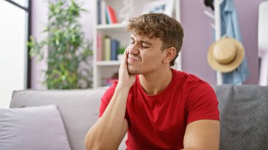 Young hispanic man stressed sitting on sofa at home