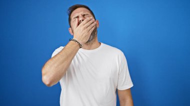 Beyaz gömlekli, yorgun ve olgun bir adam. Mavi arka planda esniyor..