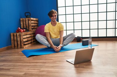 Young caucasian man smiling confident having online stretching class at sport center