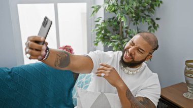 Sakallı yakışıklı adam sıcak bir oturma odasında selfie çekiyor..