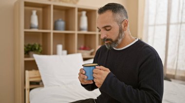 Sakallı, olgun bir İspanyol, rahat ve huzurlu bir yatak odasında kahveden zevk alır..