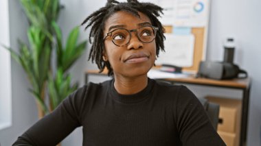 Ofisinde dürbünlü gözlüklü genç siyahi bir kadının portresi.