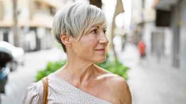 Beyaz saçlı, olgun İspanyol bir kadın şehir sokaklarında eğleniyor.