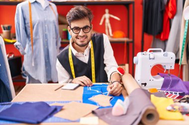 Genç İspanyol terzi gülümsüyor atölyedeki kumaşta iz bırakıyor.