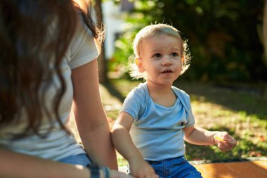 Anne ve oğlu bankta oturup parkta küçük solucanlar yiyorlar.