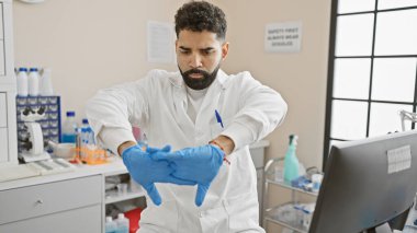 Laboratuvar önlüğü giyen sakallı genç adam klinikte çalışmaya hazırlanıyor.