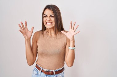 Young hispanic woman standing over white background celebrating mad and crazy for success with arms raised and closed eyes screaming excited. winner concept 