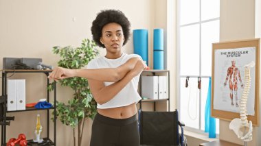 Afrika kökenli Amerikalı bir kadın modern kapalı bir spor salonunda esniyor, sağlık ve zindelik gösterisi yapıyor..