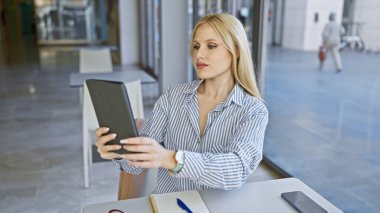 Şehirdeki bir kafede otururken tablet kullanan odaklanmış bir iş kadını..
