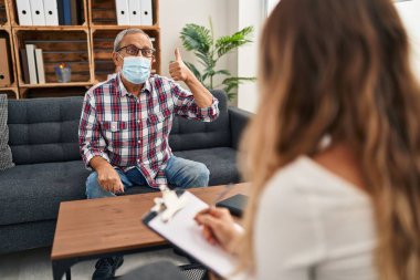 Tıbbi maskeli neşeli kıdemli adam psikoloji kliniğinde havalı bir 