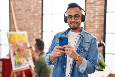 Two men artists smiling confident drawing and listening to music at art studio