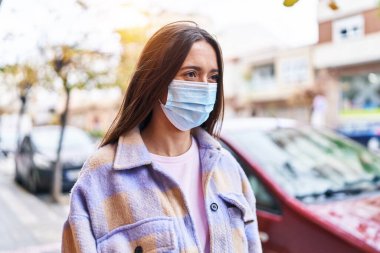 Sokakta duran, tıbbi maske takan genç, güzel İspanyol kadın.