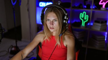 Karanlık bir odada oynayan, kulaklık takan, kırmızı bluzlu, beyaz bir kadın.