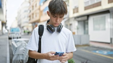 Şehir caddesinde akıllı telefon kullanan genç, beyaz bir erkek..