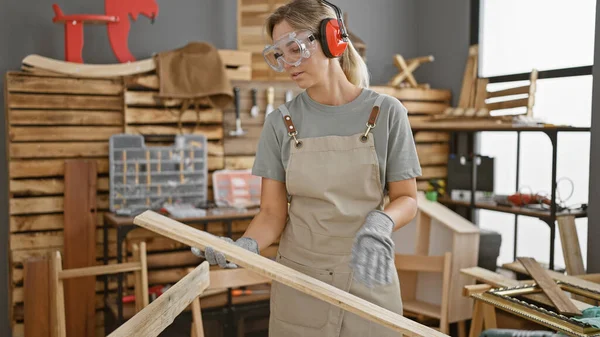 Kobieta Okularach Ochronnych Bada Drewnianą Deskę Dobrze Wyposażonej Stolarni — Zdjęcie stockowe