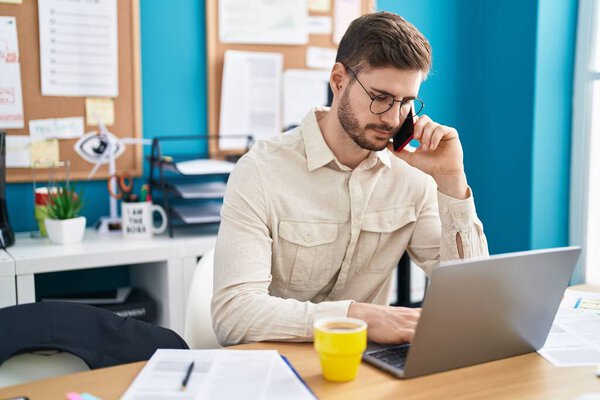 Young caucasian man business worker using laptop talking on smartphone at office