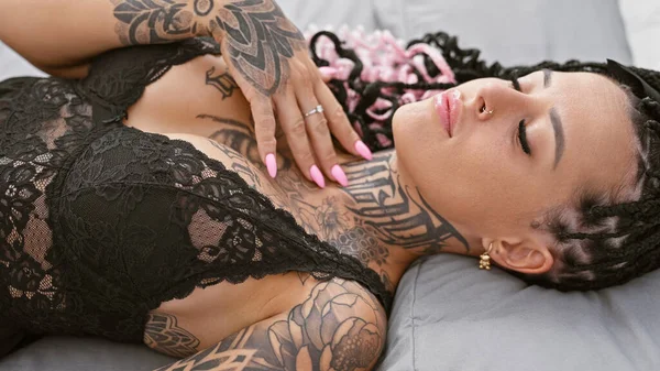 Yorgun ama güzel, genç İspanyol bir kadın sabah ışığında rahat bir şekilde rahat yatak odasında, yumuşak yastıklar ve battaniyelerin arasında yatıyor.