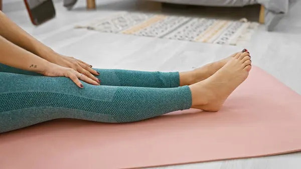 Sporty female stretching her legs on a yoga mat at home, a healthy, athletic woman embracing fitness in her living room
