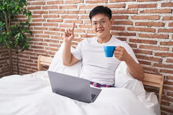 Genç Asyalı bir adam yatakta oturmuş kahve içerken bir fikre ya da soru işaretine şaşırdı. 