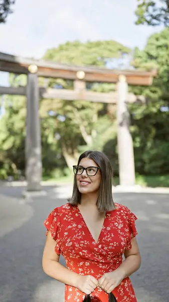 陽気で美しいヒスパニック系女性が眼鏡をかけ 喜んで立って周りを見回し 東京明治寺のポジティブなバイブを楽しんでいます — ストック写真