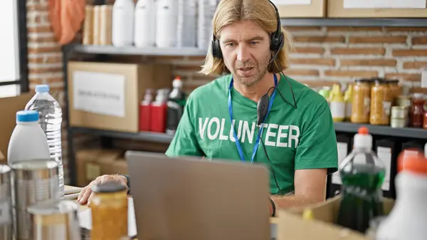 Blond Man Wearing Headset Green Volunteer Shirt Focusing Laptop Warehouse — Stock Photo, Image