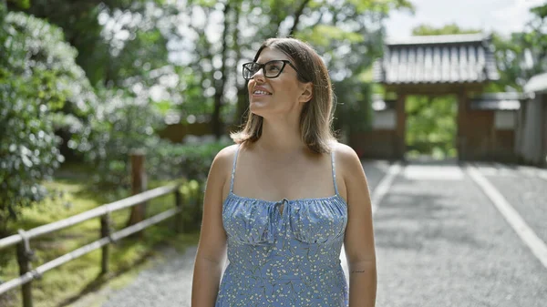 İspanyol kadın, gözlüklü ışıldayan güzellik ve neşe, Kyoto tapınağında neşeli bir ifadeyle etrafa bakıyor, Japon mimarisinin ortasında güvenle duruyor, huzurun tadını çıkarıyor..