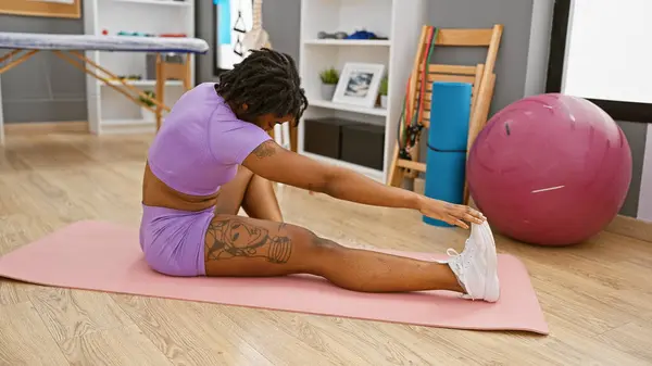 Rastalı Afrikalı bir kadın modern kapalı bir spor salonunda esniyor..