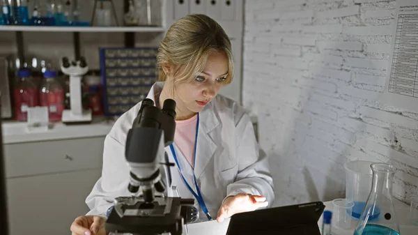 若い白人女性科学者は 医療機器に囲まれた実験室でのタブレットの結果を分析する — ストック写真