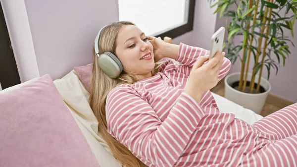 Young Woman Lounges Her Bedroom Enjoying Music Her Headphones While — Stock Photo, Image