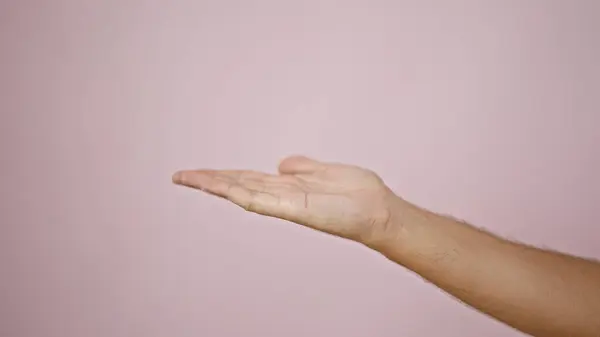 A close-up of a man\'s extended hand against a plain pink background, suggesting aid or offering.