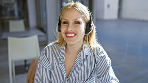 笑顔の若い金髪の女性と街の屋外に座っているヘッドフォン — ストック写真