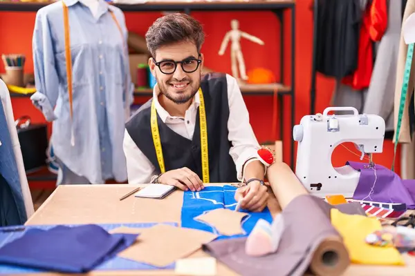 Genç İspanyol terzi gülümsüyor atölyedeki kumaşta iz bırakıyor.