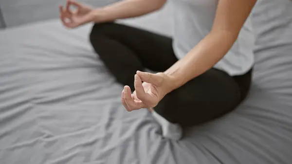 Awake woman, in sportswear, finds calm balance sitting on bed, hands poised in meditative yoga exercise. invokes relaxation and concentration within the comfort of her cozy bedroom.