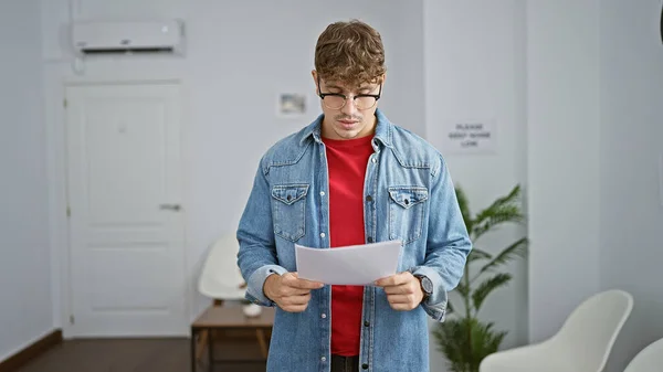 ハンサムな若いヒスパニックの男性は 忙しい待合室に立って 屋内廊下の背景の中で答えを探しながら 文書を読むことに真剣に興奮しました — ストック写真