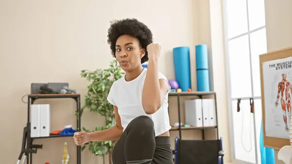 stock image African american woman exercising in a bright, well-equipped indoor gym, showcasing fitness and health.