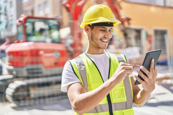 Young hispanic man architect using touchpad at park