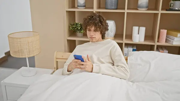 Young Man Curly Hair Using Smartphone While Relaxing Cozy Bedroom — Stock Photo, Image