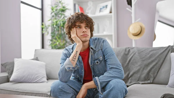 Modern apartman dairesinde oturan sakallı ve dövmeli yakışıklı, düşünceli İspanyol adam.