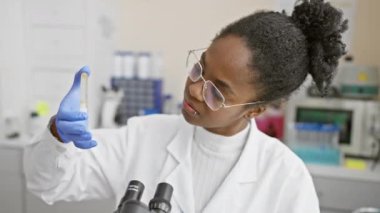Afro-Amerikalı kadın bilim adamı laboratuarda örnek analiz ediyor.