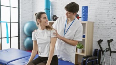 Kadın hasta ve erkek fizyoterapist, parlak bir fizyoterapi kliniğinde dostça vakit geçiriyorlar..