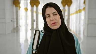 Tesettürlü düşünceli bir kadın Abu Dabi 'de zarif İslami mimarisi olan bir camide duruyor..