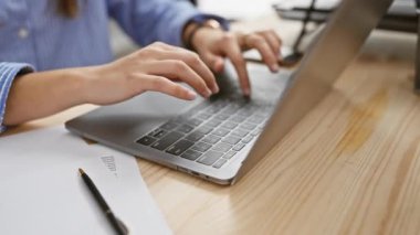 Profesyonel genç bir kadın, modern ofis ortamında özenle dizüstü bilgisayarına yazar, verimliliği ve teknolojiyi iş yerinde vurgular..
