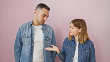 Kot gömlek içinde neşeli güzel bir çift, pembe izole arka planda dikiliyor, neşeli gülümsemeler gösteriyorlar ve doğrudan kameraya bakıyorlar..