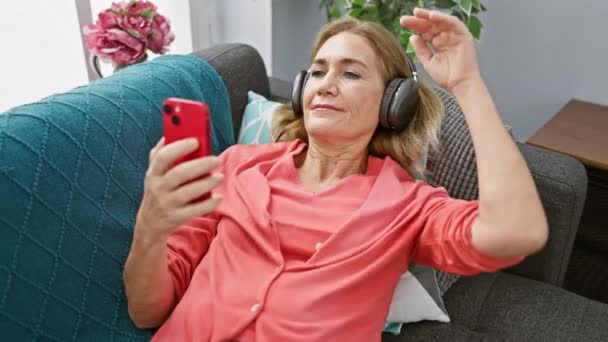 Mulher Madura Desfrutando Música Com Fones Ouvido Smartphone Uma Acolhedora — Vídeo de Stock