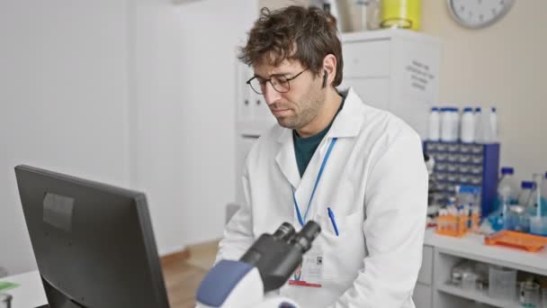 Homem Hispânico Focado Trabalhando Computador Ambiente Laboratorial Usando Jaleco Óculos — Vídeo de Stock