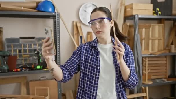Young Caucasian Woman Safety Glasses Uses Smartphone Woodwork Workshop Showcasing — Stock Video